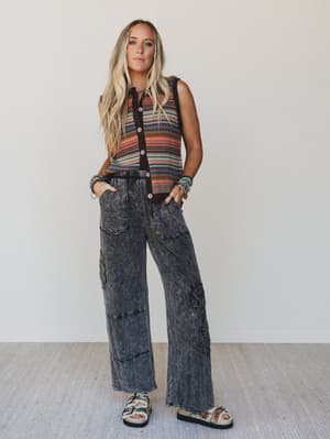 Woman wearing a sleeveless striped top and acid-wash jeans against a plain background