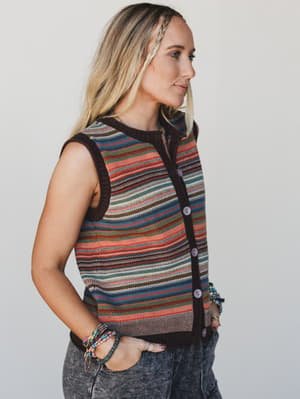 Woman wearing a colorful striped sleeveless sweater against a plain background