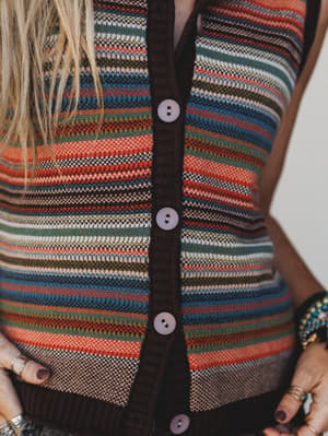 Close-up of a person wearing a colorful striped cardigan with buttons.