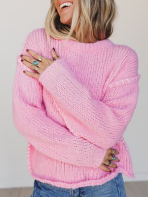Person wearing a pink sweater with a plain background