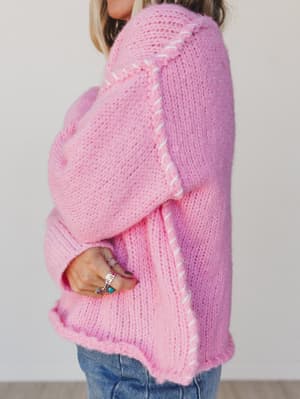 Person wearing a pink knitted cardigan with a white background