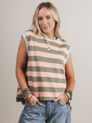 Woman wearing a striped sleeveless top and jeans against a plain background