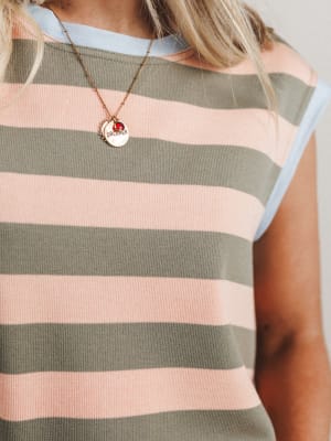 Person wearing a striped shirt with a necklace featuring a red pendant.