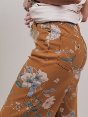 Brown floral pants worn by a person on a plain background