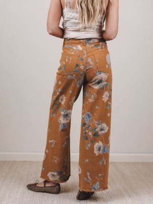 Person wearing mustard yellow floral pants against a plain background