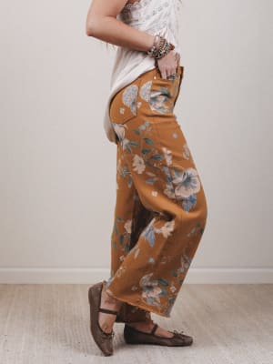 Person wearing mustard-colored floral pants with a white background