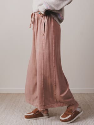 Person wearing a long pink skirt and brown shoes on a neutral background