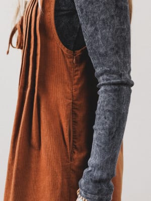 Brown corduroy dress with a gray sleeve on a plain background