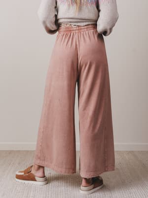 Person wearing pink wide-leg pants and a patterned sweater against a plain background