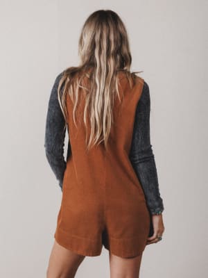 Person wearing a brown romper with a plain background