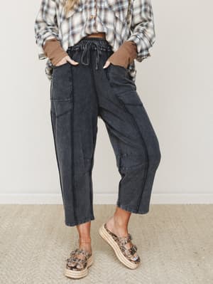 A relaxed, lived-in barrel pant in washed black styled with a plaid flannel and waffle knit cuffs — the kind of outfit that looks effortless but clearly has opinions.