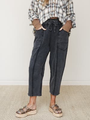 Washed black barrel-leg pants styled with a knotted plaid shirt, waffle-knit sleeves peeking through, and leopard print platform sandals — the kind of effortless, lived-in outfit that looks thrown together in the best way.