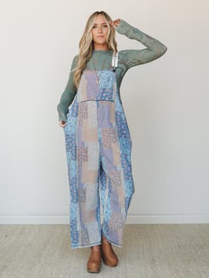 A wide-leg patchwork overall jumpsuit in soft blue denim tones layered over a sage green lace long-sleeve top — the kind of outfit that looks like it was styled effortlessly but definitely wasn't accidental.