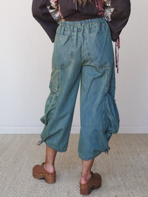 Shot from behind, this look pairs wide-leg denim cargo pants in a faded, lived-in wash with a dark boho top and chunky wood clogs — the kind of outfit that looks effortless but totally thought-out.
