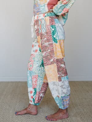 A side-profile shot of relaxed patchwork harem pants layered with a matching printed top — every panel tells a different story, and together they feel like a quilt someone actually wants to wear.