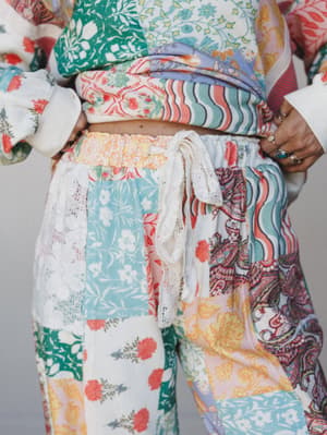 A close-up torso shot of a patchwork set in full bloom — wide-leg pants and a cropped top layered together in a kaleidoscope of floral, paisley, and wave prints, tied at the waist with a delicate lace drawstring.