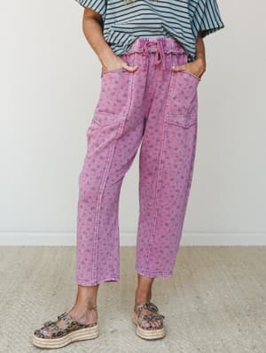 A cropped, relaxed-fit floral pant in washed magenta styled with a blue striped top and leopard print platform sandals — casual and playful with a lived-in, vintage feel.