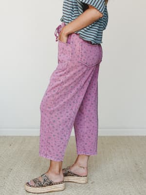 A side-profile shot of wide-leg cropped pants in washed magenta with an all-over ditsy floral print, styled with a blue striped tee and leopard print platform espadrilles — the kind of outfit that looks effortless but is clearly thought out.