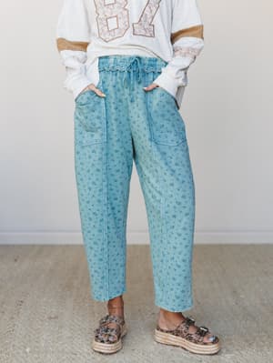 Floral-printed teal barrel-leg pants styled with a vintage varsity sweatshirt and platform sandals — the kind of effortless combo that looks like you tried just enough.