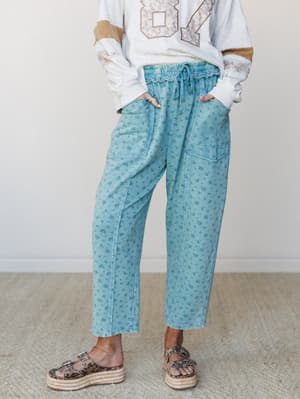 Relaxed floral-printed pants in a faded teal blue paired with a graphic sweatshirt and platform sandals — the kind of outfit that looks effortless but was definitely thought about.