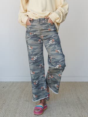 Wide-leg camo pants with scattered floral print styled with a soft yellow sweatshirt and rainbow platform sandals — the kind of outfit that feels effortless but clearly thought about.