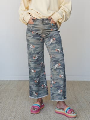 Wide-leg camo pants with scattered floral print styled with a soft yellow sweatshirt and rainbow platform sandals — the kind of outfit that looks effortless but definitely had a moment in front of the mirror.