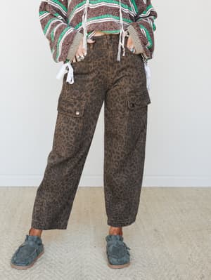 Leopard-print barrel cargo pants styled with a striped boho sweater and slate suede loafers — earthy, relaxed, and a little wild in the best way.