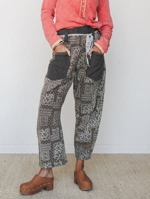 A relaxed wide-leg pant in an earthy ash-toned bandana patchwork print, styled with a coral long-sleeve top and wooden clogs — the kind of outfit that looks effortless but is clearly very much on purpose.