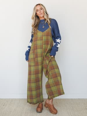 A wide-leg plaid jumpsuit in olive and rust layered over a navy star-print sweater — the kind of effortlessly thrown-together fall outfit that looks like it took zero effort and actually took all the right effort.