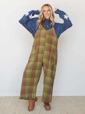 A wide-leg plaid jumpsuit in olive and rust layered over a denim blue star-print sweater — the kind of outfit that makes a Tuesday feel intentional.