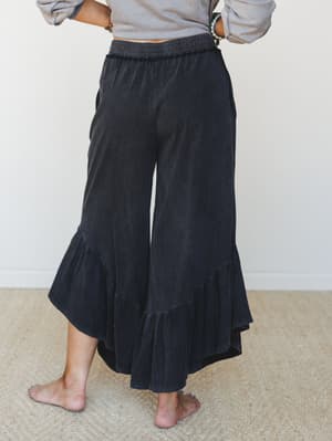 Wide-leg ruffle-hem pants in a washed black with a relaxed elastic waistband, styled with a cropped grey sweatshirt — the kind of effortless combo that makes cozy look intentional.