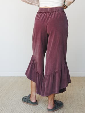 Shot from behind, these wide-leg ruffle-hem pants in a washed mulberry hue feel like the comfy-cool middle ground between staying in and going out — styled with a sheer polka dot top and slip-on shoes for an effortlessly relaxed look.