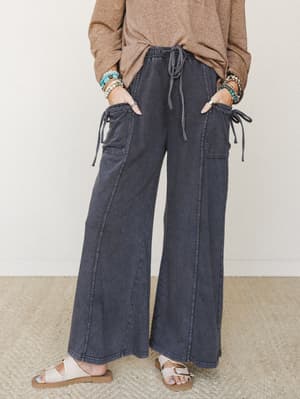 Wide-leg cargo pants in a washed ash charcoal, styled with a knotted camel top, beaded bracelets, and sandals — the kind of effortless outfit that looks like you tried just enough.
