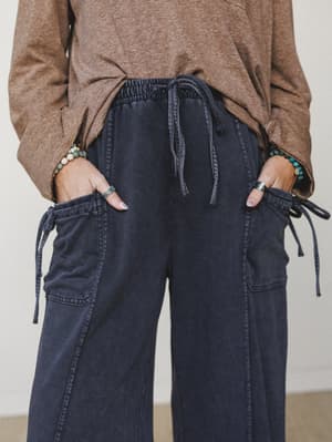 A close-up torso shot of wide-leg cargo pants in a washed ash navy, styled with a heathered mocha long-sleeve top and layered bead bracelets — the kind of effortless combo that looks intentional without trying.