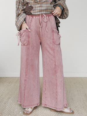 Wide-leg cargo pants in a faded dusty rose mineral wash, styled with a plaid top and sandals — the kind of pants that feel like a soft day and still look like you tried.