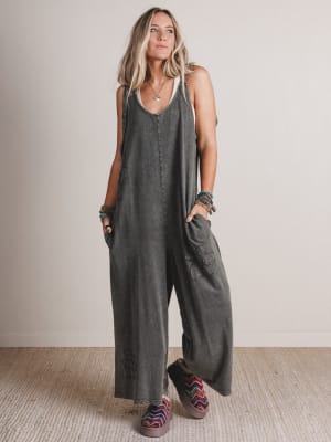 Woman wearing a gray jumpsuit standing against a plain background