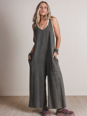 Woman wearing a gray jumpsuit standing against a plain background