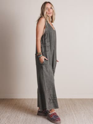 Woman wearing a gray jumpsuit standing against a plain background