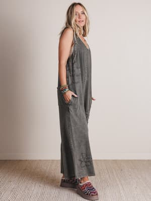 Woman wearing a gray jumpsuit standing against a plain background