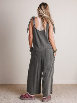 Person wearing a gray jumpsuit with patterned sleeves against a plain background