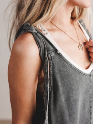 Person wearing a gray sleeveless top with lace trim and a necklace.