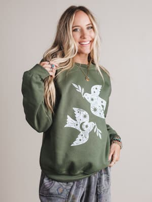 Woman wearing a green sweatshirt with a white dove design on a plain background