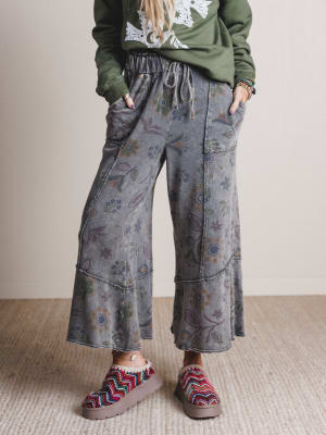 Person wearing floral-patterned pants and colorful shoes on a neutral background