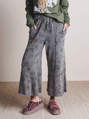 Person wearing floral-patterned pants and colorful shoes on a neutral background