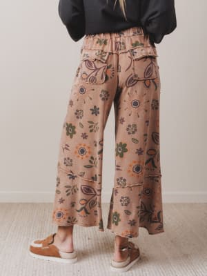Person wearing floral-patterned pants on a plain background