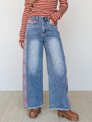 Wide-leg washed denim jeans with plaid side panel inserts and a frayed hem, styled with a rust stripe knit top and wood-studded clogs — the kind of outfit that feels like a record store and a farmers market in the same afternoon.