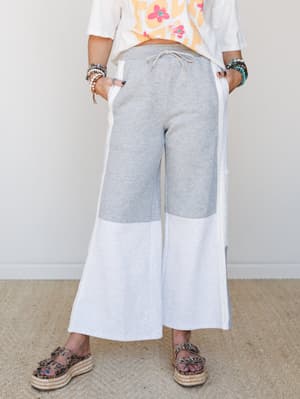 Wide-leg colorblock sweat pants in heather grey and white styled with a graphic tee, stacked bracelets, and espadrille platform sandals — the kind of outfit that looks intentional without trying too hard.