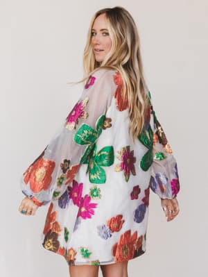 Woman wearing a colorful floral dress against a plain background