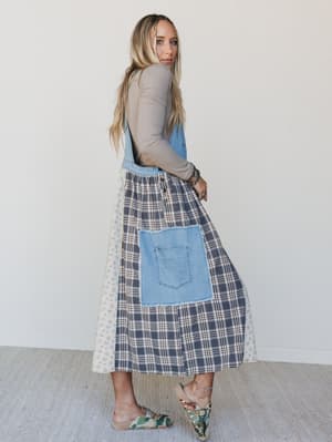 Woman wearing a plaid skirt with denim pocket and a light gray top against a white background