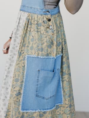 Skirt with floral pattern and denim pocket and hem on a plain background